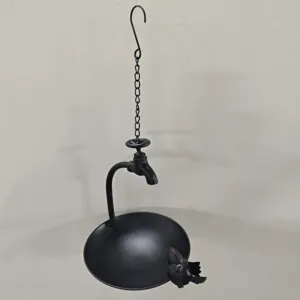 Detail of creative faucet-shaped hanging metal bird feeder with bird figurine for garden