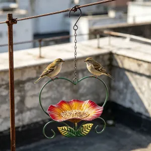 Close-up of heart-shaped flower bird feeder with two birds feeding on a rooftop