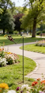 Molinillo de jardín de metal con niña y paraguas amarillo en un entorno de parque.