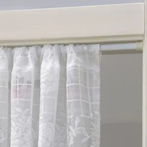 Close-up detail of white lace curtain showcasing delicate floral fabric and hanging rod setup.