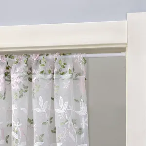 White sheer door curtain with pink and green floral embroidery detail closeup hanging on rod