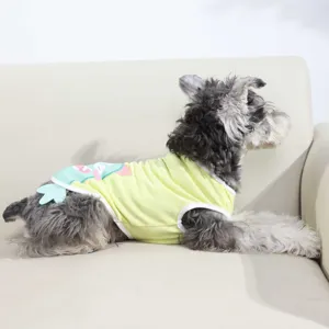 Detailed shot of a cute puppy wearing a breathable yellow summer vest with cartoon print on back.