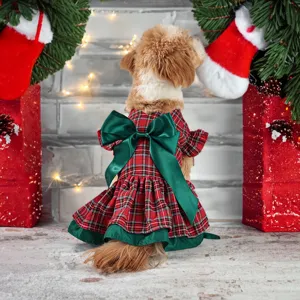 Detailed view of cute pet dog Christmas plaid dress with big green bow and festive holiday backdrop.