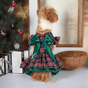 Detailed view of the Christmas pet dress with green satin bow and festive plaid fabric setup.