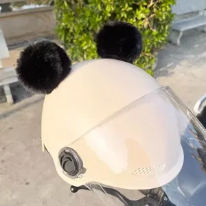Detailansicht süßer schwarzer flauschiger Bommelohren auf beiger Motorradhelm mit Visier.
