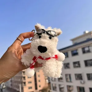 Detail view of cute white West Highland Terrier plush keychain with goggles and scarf.