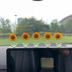 Detail shot of cute sunflower car bobblehead ornaments with vibrant petals and spring bases.