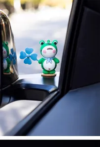 Cute green frog car ornament with blue clover spinner, perfect vehicle interior design.