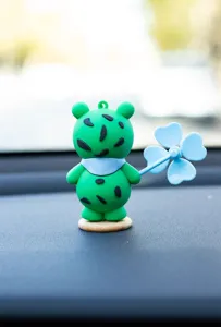 Cute green frog car ornament holding blue clover pinwheel, perfect dashboard decoration for vehicles.