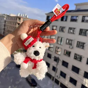 Cute white plush puppy keychain with red knitted hat and scarf, stylish bag accessory.