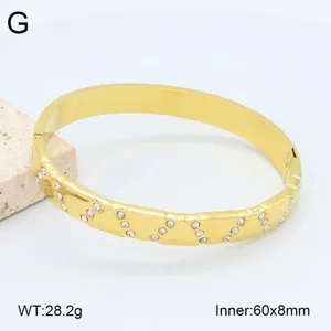 Vue de détail en gros plan du bracelet jonc en acier inoxydable doré avec des cristaux étincelants.