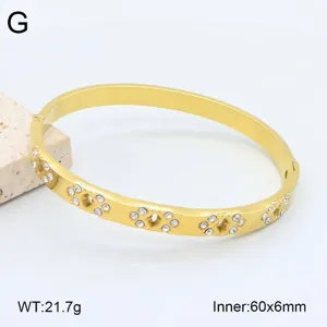 Gros plan détail du bracelet jonc ouvert en acier inoxydable doré avec strass 60x6mm.