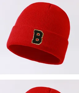 Trendy red knit beanie with black and gold letter B patch for autumn and winter outdoor wear.