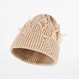 Detailopname van beige distressed gebreide muts, uniek gescheurd gatenontwerp, comfortabele muts.