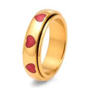 Detaillierte Makroansicht eines goldenen Titan-Spinnerrings mit roten Emaille-Herzen.