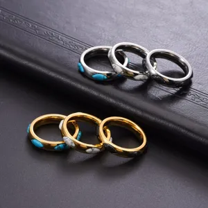 Primo piano di anelli in acciaio al titanio con pietre marquise in oro e argento