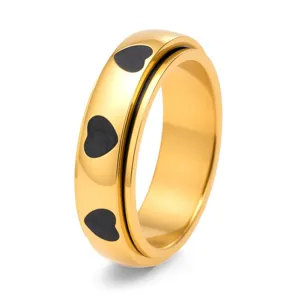 Detailansicht eines goldenen Spinner-Rings mit gravierten schwarzen Herzmustern.