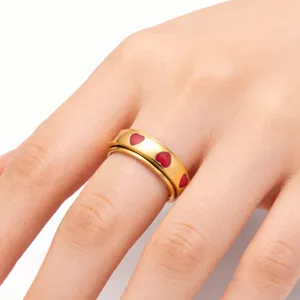 Detailansicht eines goldfarbenen Edelstahl-Spinner-Rings mit roten Emaille-Herzen