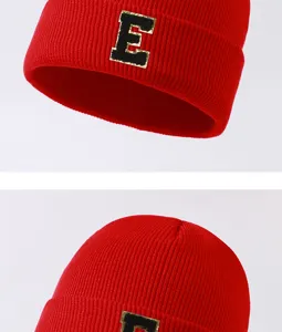Close-up detail of the red knitted beanie showing the stylish letter E patch embroidery.