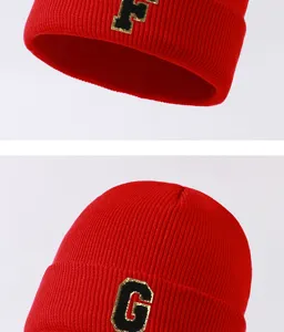 Closeup details of the red knit beanie hat, featuring stylish black and gold letter patch.
