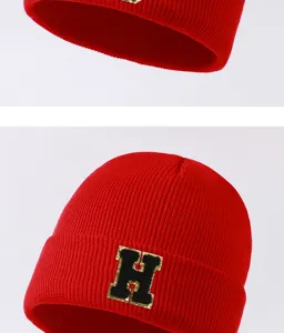 Red knitted beanie winter warm cold-proof hat with black gold letter H patch detail view