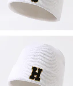 Nahaufnahme einer weißen Strickmütze mit Buchstabenstickerei, warm und modisch für Winter.
