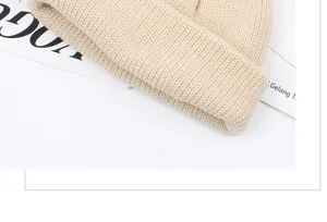 Detailed view of the beige knitted beanie, showing soft texture and cozy ribbed cuffed style.