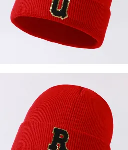 Red knitted beanie hat detail showing stylish collegiate letter patch for autumn winter warmth.