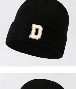 Black knitted beanie hat with white letter D patch detail. Warm winter streetwear style.