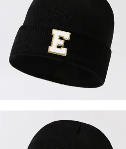 Black knit beanie hat with golden border letter E patch detail for stylish winter warmth.
