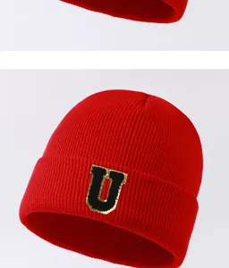 Close-up view of the red winter knitted beanie hat with a stylish black and gold letter U patch.
