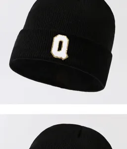 Close-up detail of a black knitted beanie featuring a stylish white letter Q patch design.