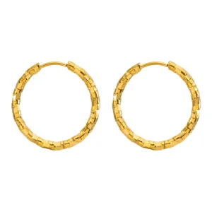 Nahaufnahme von goldenen Edelstahl-Creolen mit eleganter strukturierter Ziegeloptik
