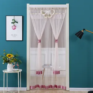 Detailed view of the pink lace door curtain with delicate butterfly decor in a cozy room setting.