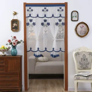 Cortina de puerta transparente blanca con bordado floral azul y bordes festoneados.