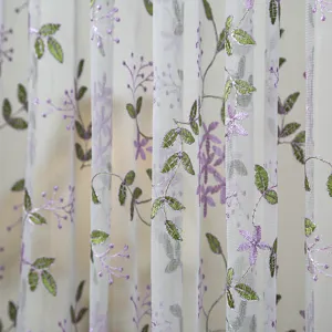 White sheer window curtain with elegant embroidered green leaves and purple floral vines.