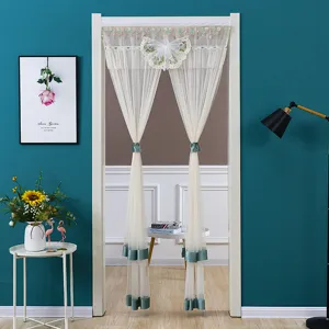 Lace door curtain detail with double gauze layers and butterfly bow tiebacks for room decor.