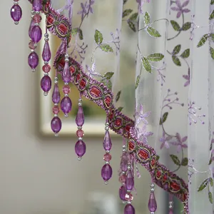 Close-up view of elegant purple beaded lace curtain detail with embroidery floral design for home décor.