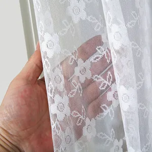 Λεπτομέρεια υφάσματος λευκής δαντελωτής κουρτίνας με διαφανή υφή και λουλουδένιο σχέδιο.