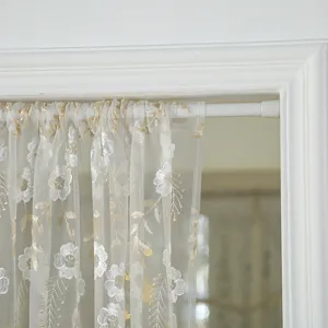 Close up of french vintage floral lace door curtain detail, sheer white fabric with gold embroidery.