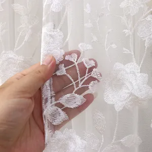 Vista de detalle de cerca de tela de cortina transparente blanca con diseño bordado.