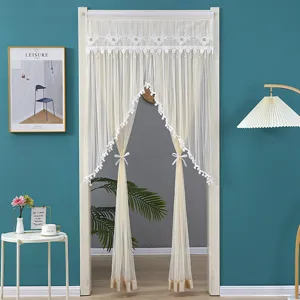 Detail view of cream white lace door curtain with cute pom pom trim and elegant tiebacks.