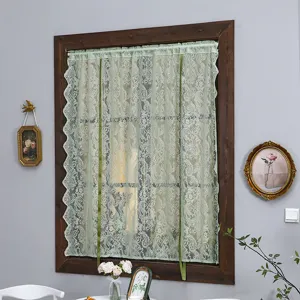 Detail view of the French vintage green lace curtain hanging on wooden window frame.