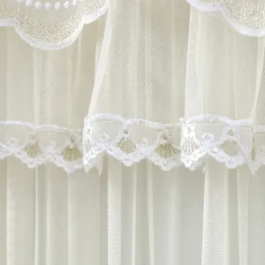 Detailed shot of white sheer mesh curtain with delicate gold embroidered scalloped lace edge.