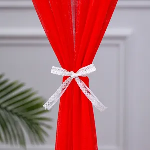 Detail view of red tulle door curtain decorated with elegant white lace bow for home decor.