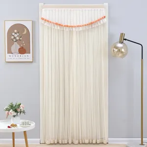Detail view of white lace door curtain with orange pom-poms in cozy bedroom scene setup.
