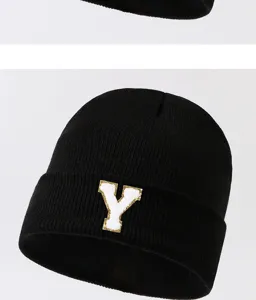 Close-up detail of the black knitted beanie featuring a white and gold letter Y patch.