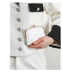 Detail shot of a white leather kiss lock coin purse with vintage gold frame and floral deboss.