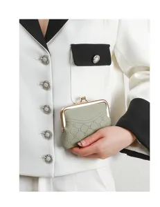 Sage green kiss-lock coin purse detail with debossed clover pattern and compact wallet.