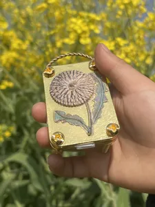 Detailansicht einer goldenen Mikro-Blumenpresse aus Metall mit einer Löwenzahngravur